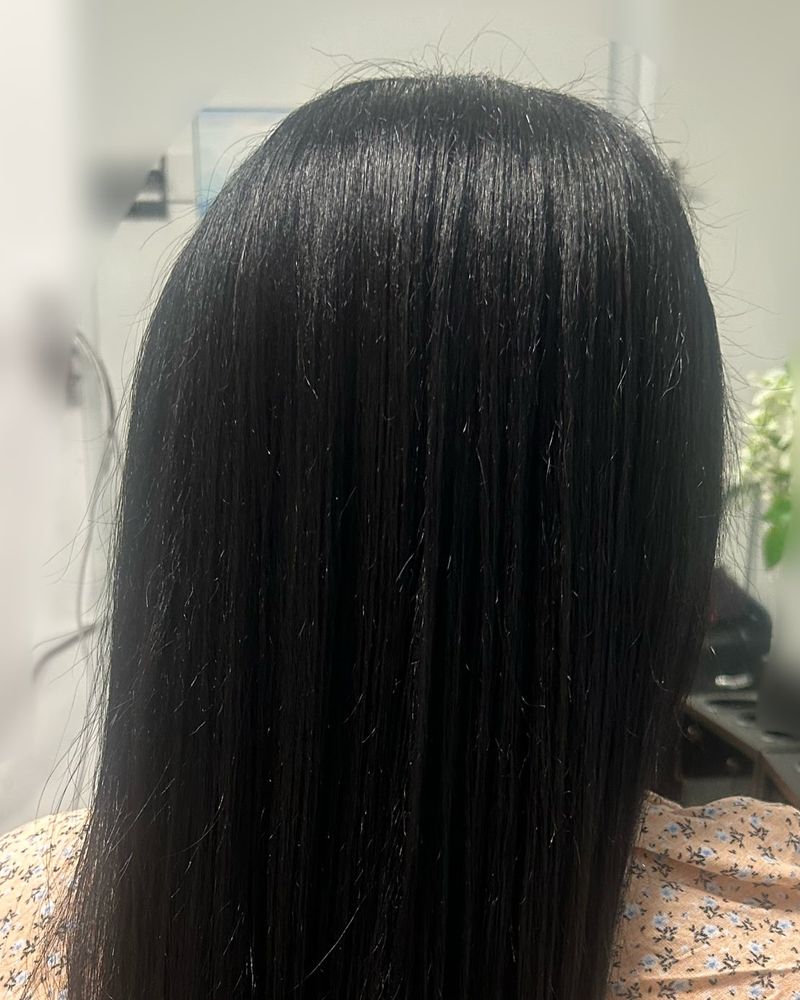 Long, sleek silk press on jet-black hair, seen from behind