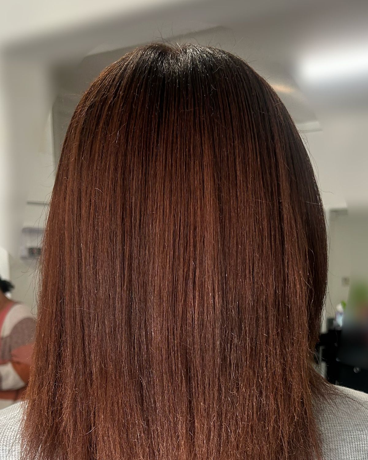 Shoulder-length silk press on auburn hair, seen from behind