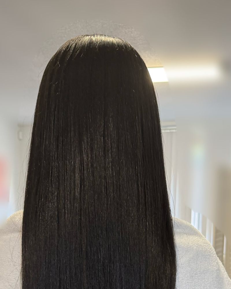 Long black silk press finished with soft curled ends, seen from behind