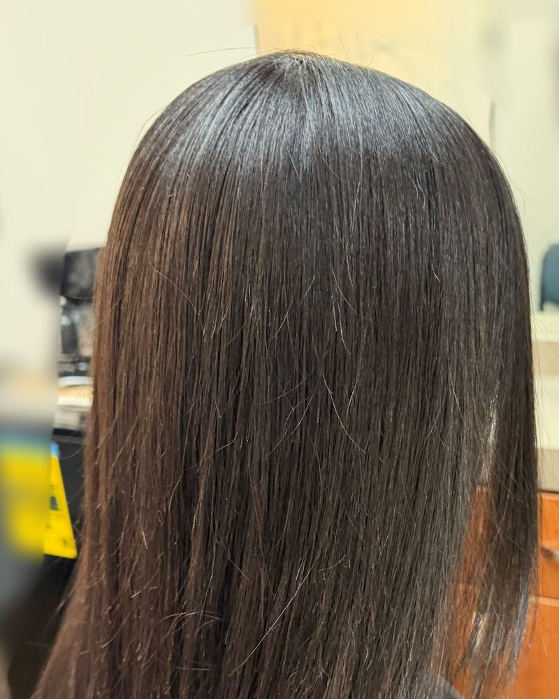 Glossy silk press on long dark brown hair, seen from behind at an angle